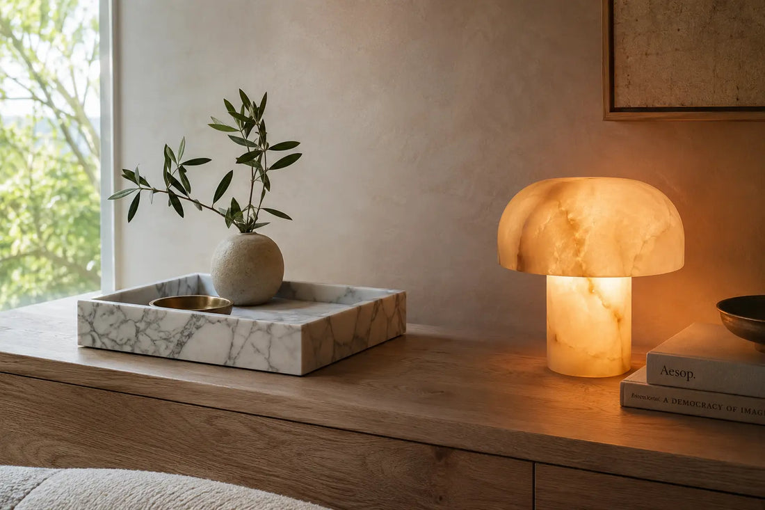 Marble tray and illuminated onyx lamp styled together in a neutral interior, showing the visual contrast between matte marble and translucent onyx