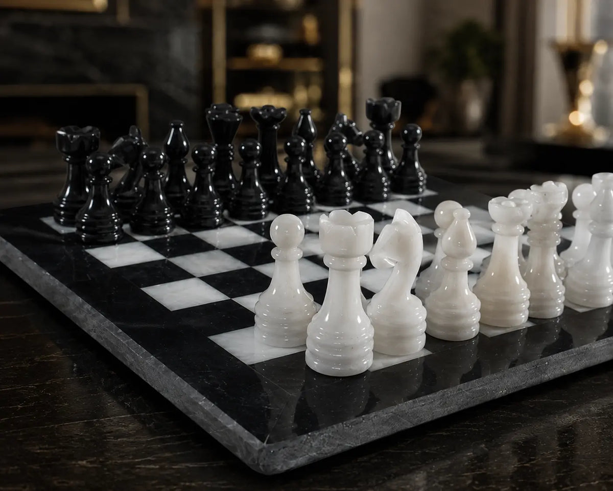 A polished black and white marble chess set on a dark wooden table, with glossy black and white chess pieces arranged on a checkered board in an elegant indoor setting.