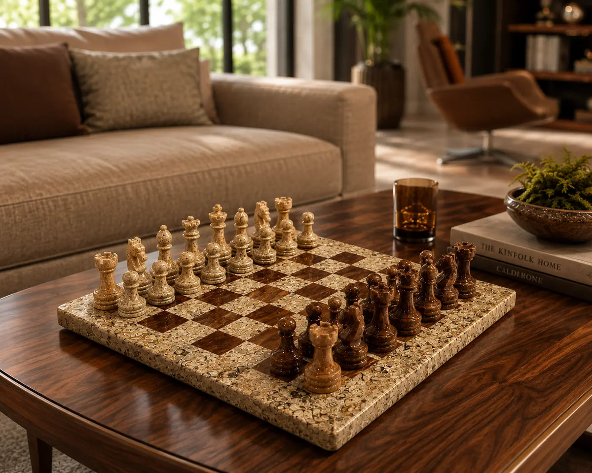 A rectangular stone chessboard with carved wooden chess pieces arranged on it, set on a dark wood coffee table in a modern living room with a sofa and chair in the background.