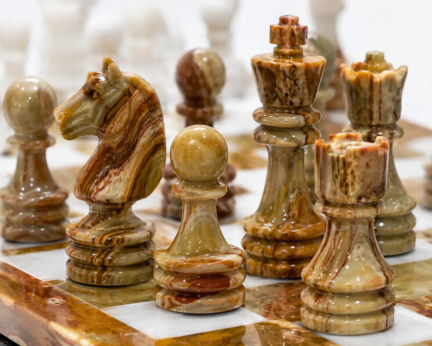 A close-up of a marble chess set with polished pieces in beige, brown, and cream tones, including a horse, pawns, rooks, and a king on a matching marble board.
