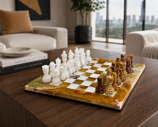 A polished stone chess set on a live-edge marble board, displayed on a dark wood coffee table in a modern living room setting.