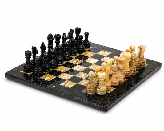 A polished stone chess set on a black and tan checkered board, featuring black and cream-colored playing pieces on a white background.