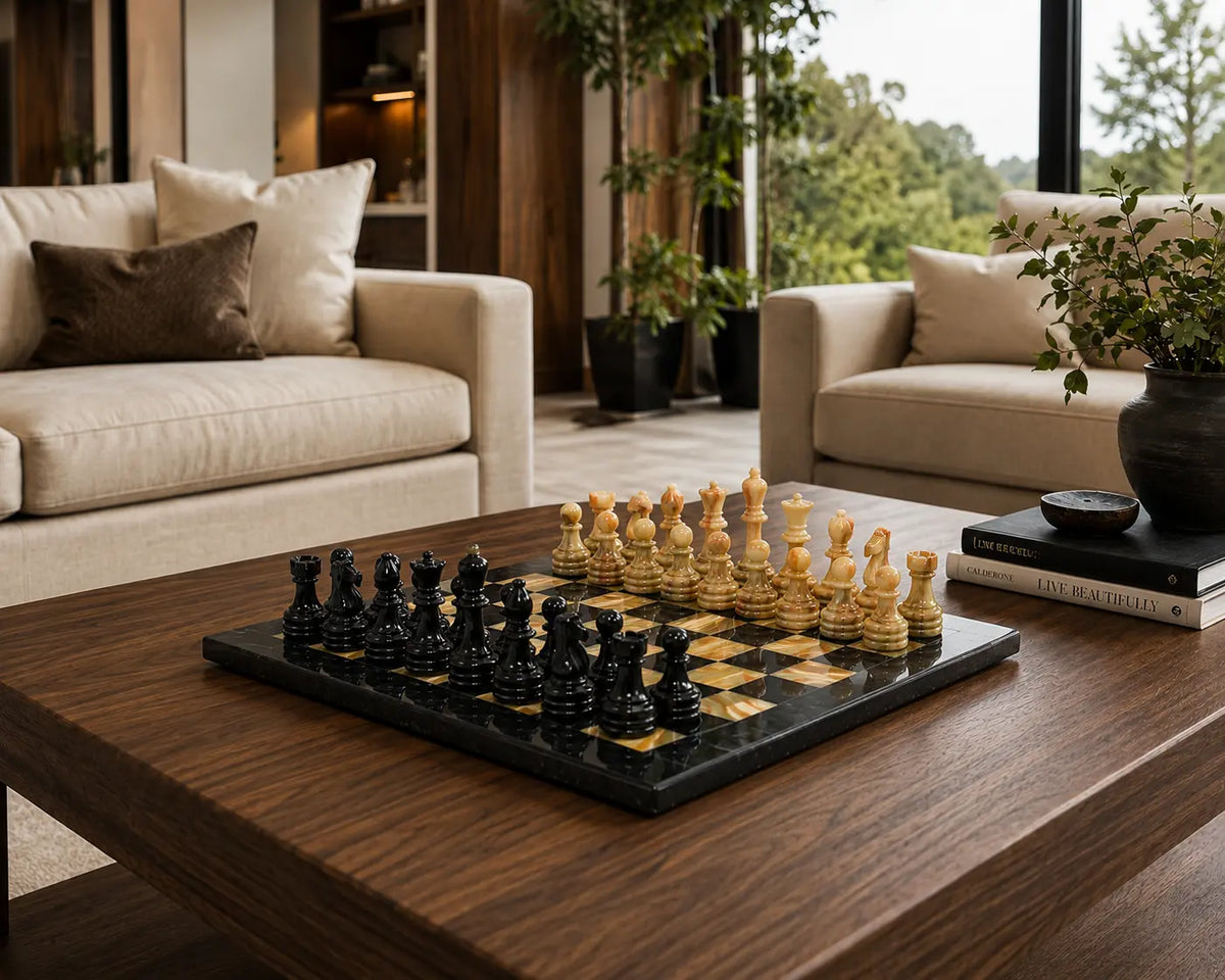 A black and natural wood chess set arranged on a dark wood coffee table in a modern living room with beige sofas and potted plants.