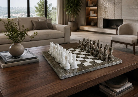 A marble chessboard with white and dark chess pieces arranged on a dark wood coffee table in a modern living room setting.